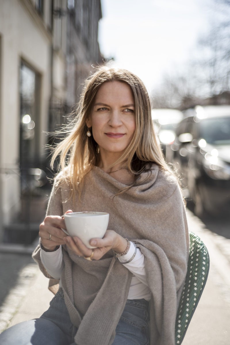 Szczęśliwa kobieta pije kawę przed kawiarnią.